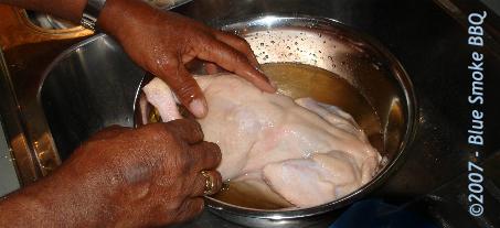 Foto van het wassen van kip in een bad van water met azijn ter voorbereiding van het grillen in oven of barbecue.