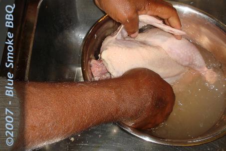 Foto van het wassen van kip in een bad van water met azijn ter voorbereiding van het grillen in oven of bbq.